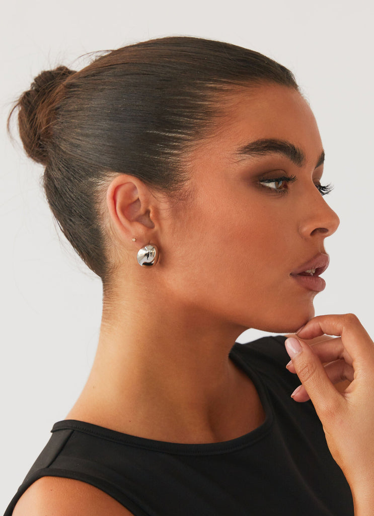 Womens Take A Bow Chunky Stud Earrings in the colour Silver in front of a light grey background