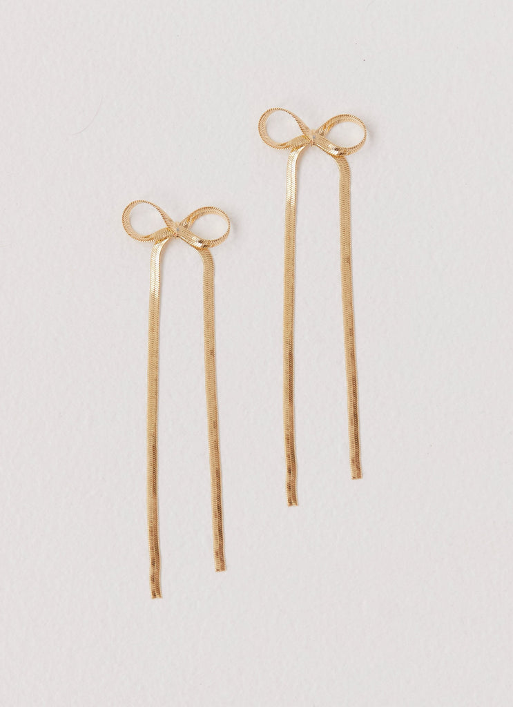 Womens Tinka Bow Earrings in the colour Gold in front of a light grey background